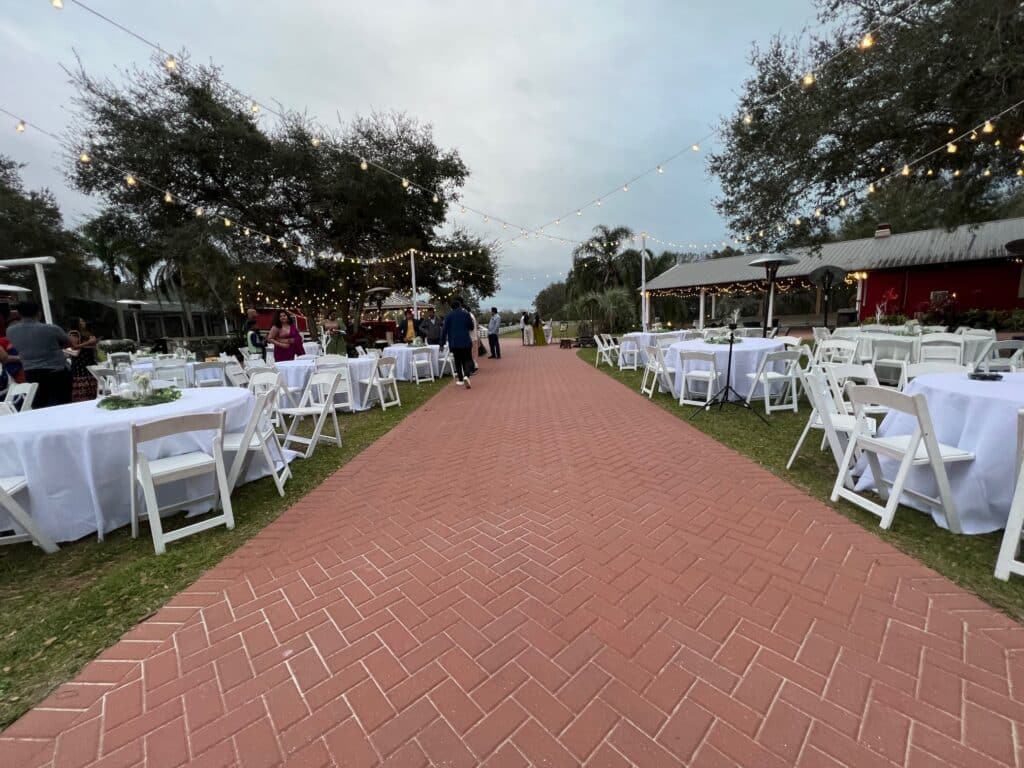 Brick courtyard path lined with white-clothed tables and string lights at the Barn Courtyard, Horsepower Ranch